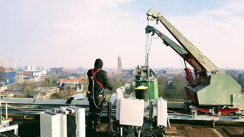 Aangelijnd werken op een dak met een gondelarm boven de stad.