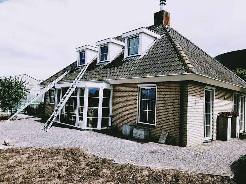 Woonhuis met twee ladders tegen het dak en een serre aan de achterzijde.