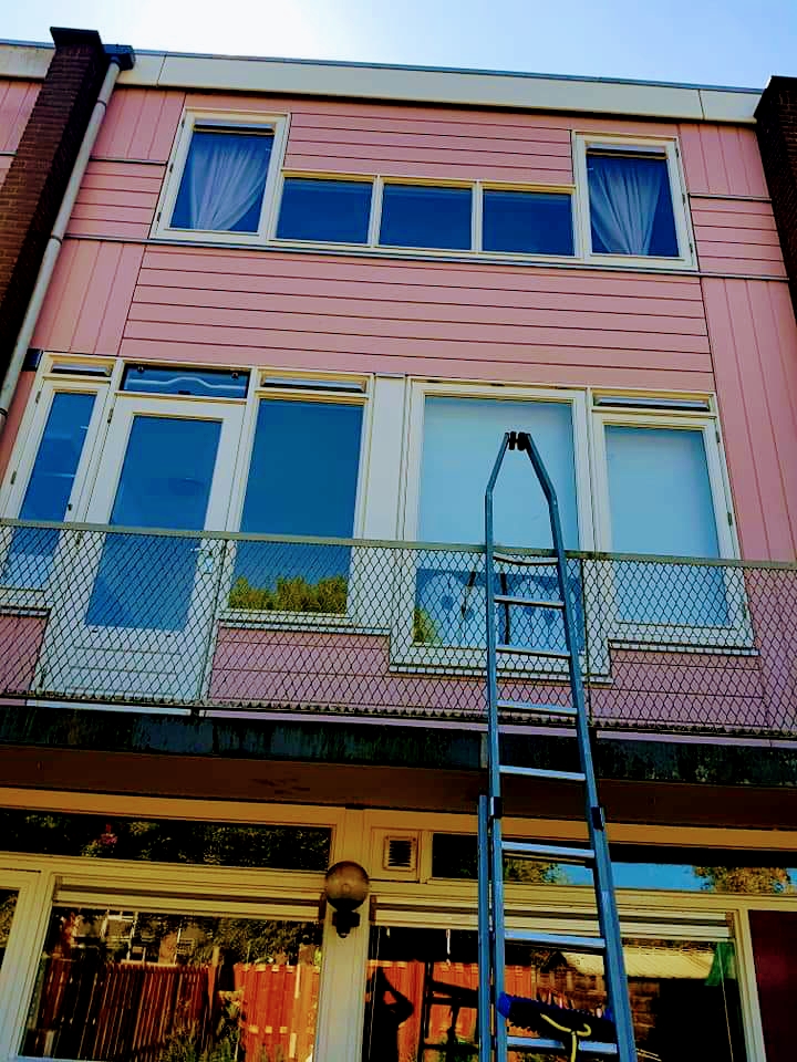 Woongebouw van drie lagen met balkons, gewassen vanaf een ladder.
